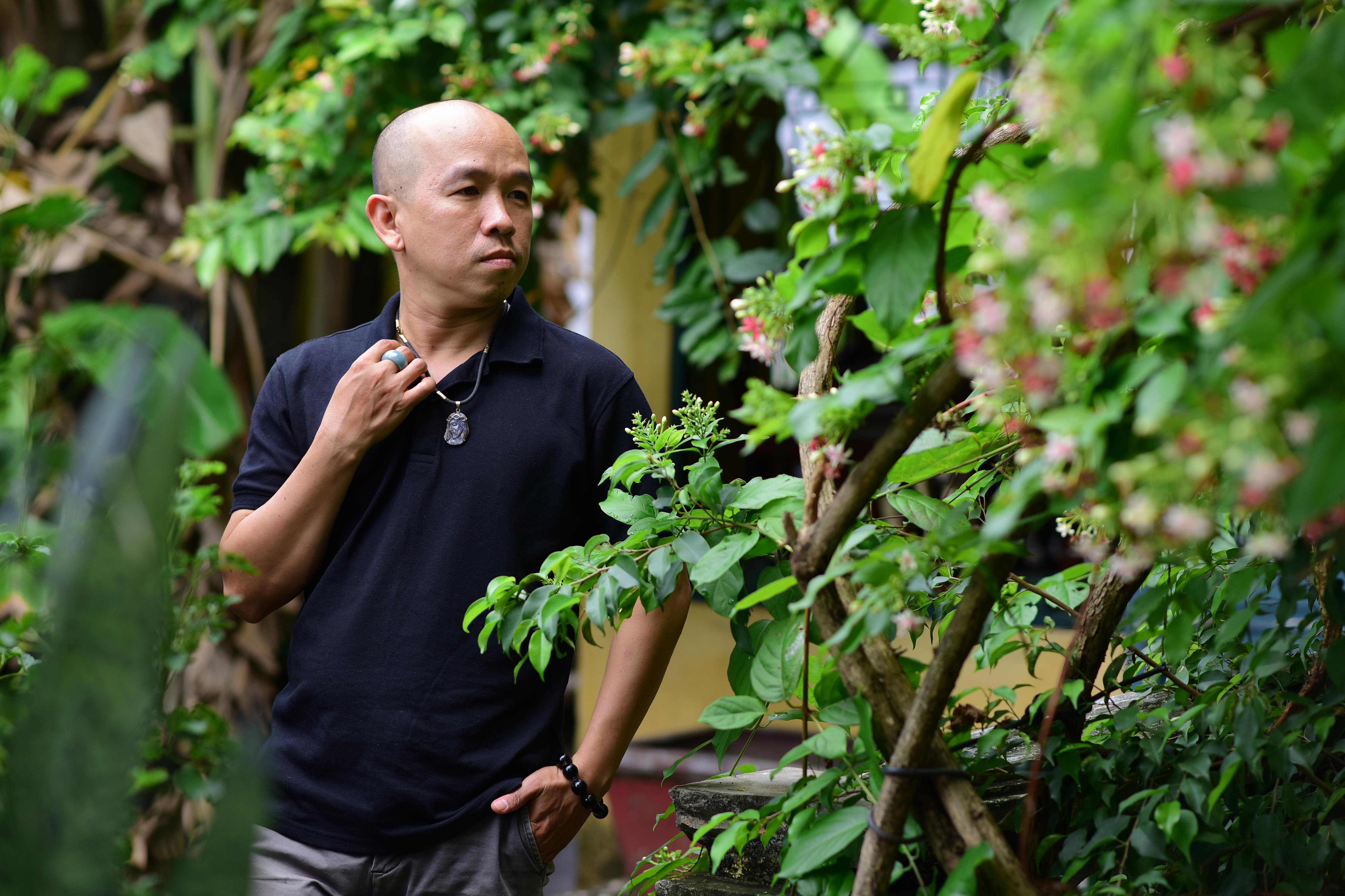 Free A man stands surrounded by lush garden greenery, reflecting in a tranquil outdoor setting. Stock Photo