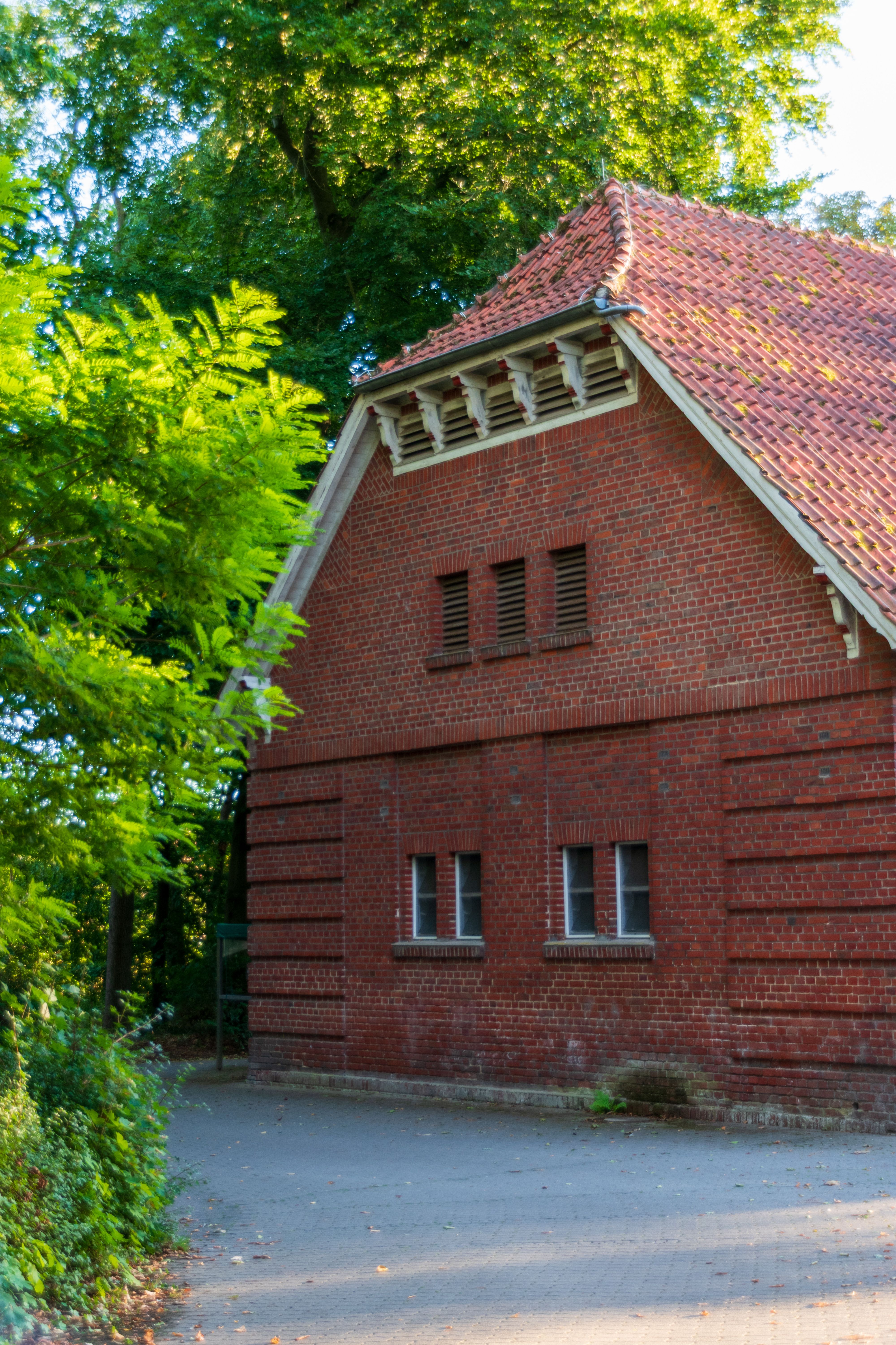 Red brick house surrounded by lush greenery in a serene outdoor setting.