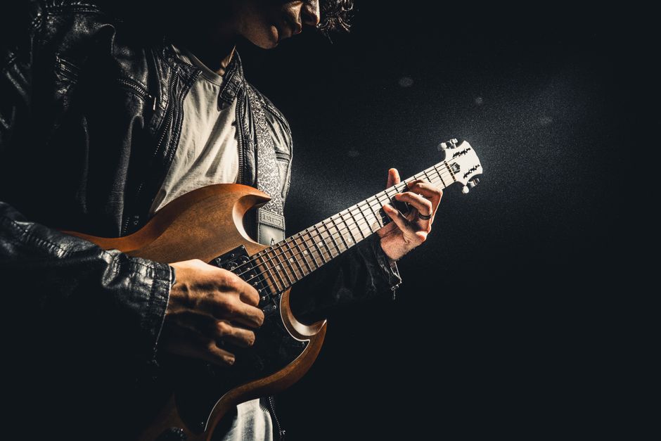 Musician's hands playing electric guitar in performance lighting`