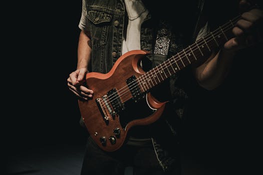 A musician passionately strumming an electric guitar with dramatic lighting.