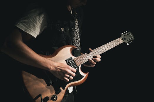 A guitarist skillfully plays an electric guitar in a dark setting, creating a moody atmosphere.