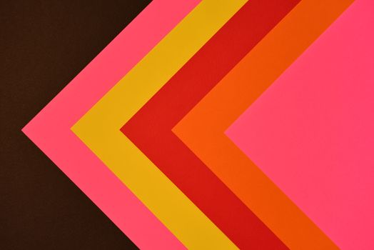 Brightly colored abstract paper arrangement forming geometric shapes on a dark background.