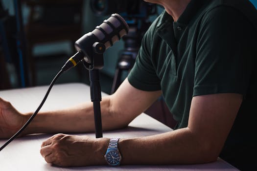Close-up of a person recording a podcast in a studio, featuring a microphone and professional audio equipment.