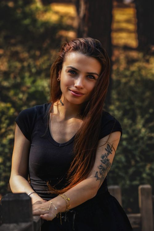 Free Charming young woman with long hair and floral tattoo posing outdoors in natural light. Stock Photo
