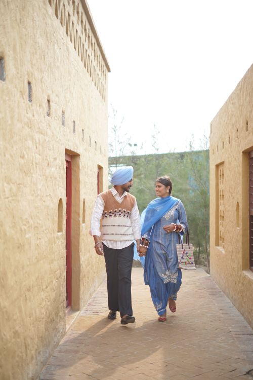 Free A couple in traditional attire walks hand-in-hand down a rustic corridor. Stock Photo