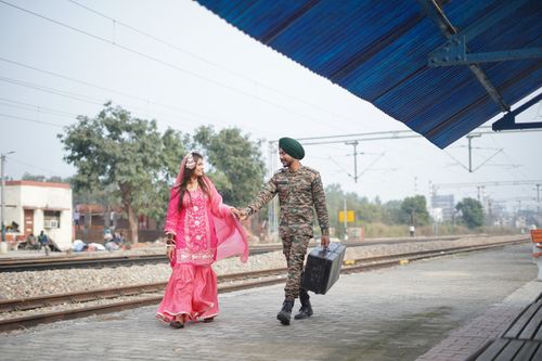 Free A smiling couple in traditional clothing walking at a railway station, exuding cultural charm and connection. Stock Photo
