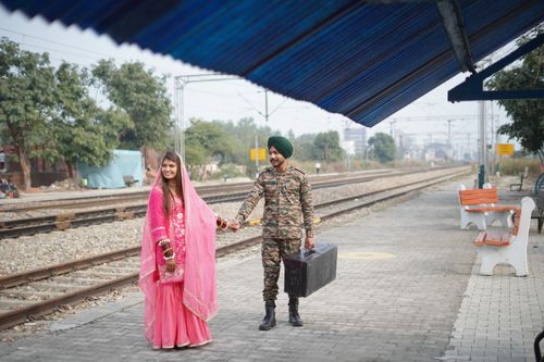 Free A couple in traditional attire smiling on a train platform, capturing a moment of joy and connection. Stock Photo