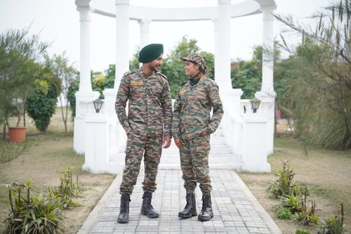 Free Two soldiers in camouflage uniforms stand outdoors, engaged in conversation. Stock Photo