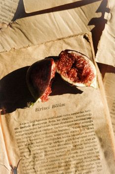 Ripe figs on aged book pages, showcasing texture and warm tones, perfect for culinary or literary themes.