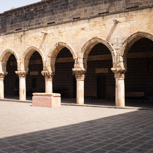 Free Ancient stone arches casting shadows in a historic courtyard under sunlight. Stock Photo