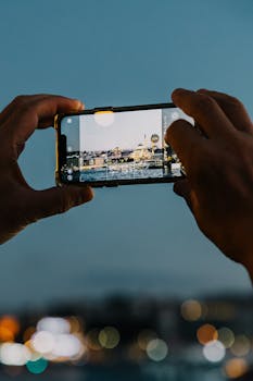 A smartphone captures Istanbul skyline including a mosque during twilight.