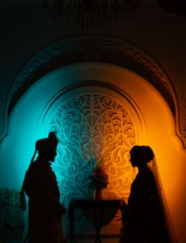 Silhouette of a couple at a wedding with vibrant blue and orange backdrop lighting.