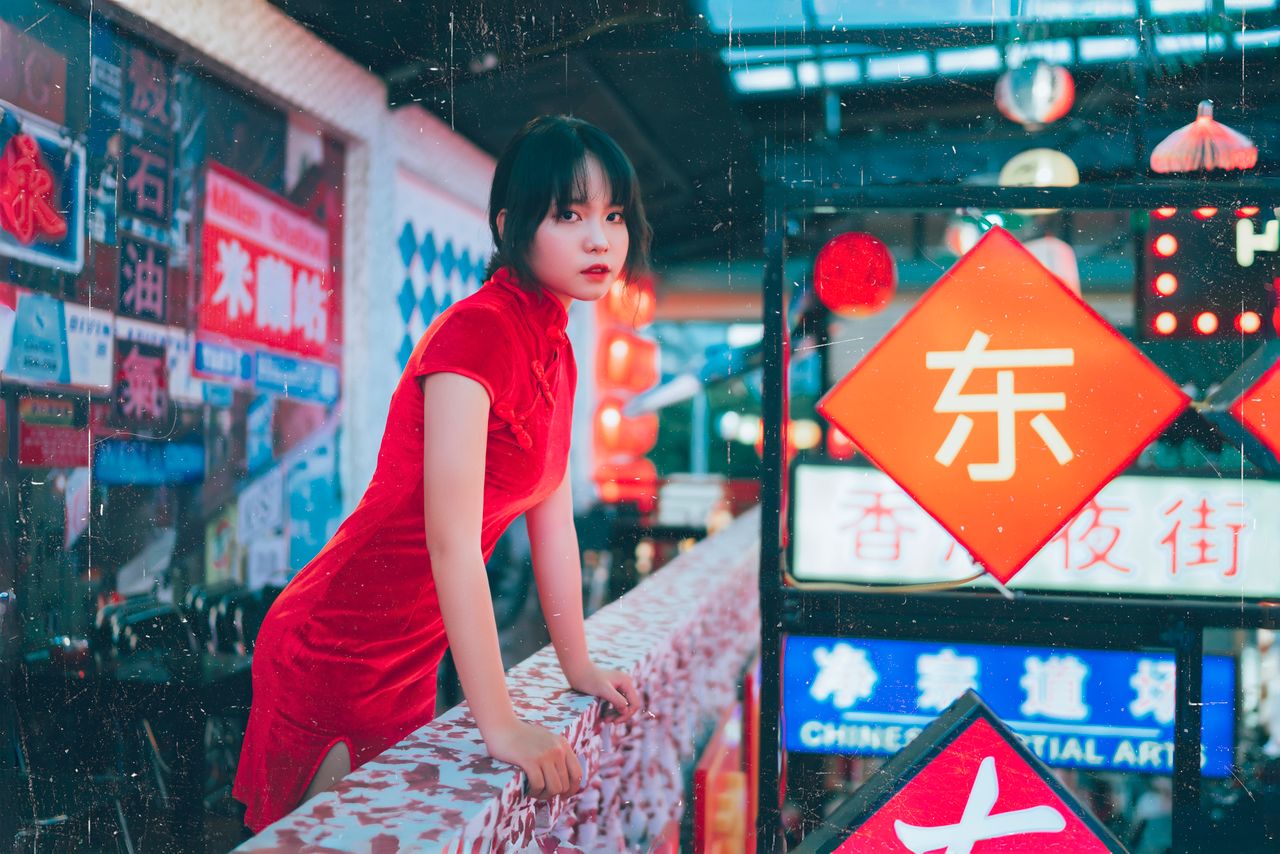 woman in elegant red dress amidst vibrant neon signs urban night scene