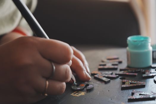 Close-up view of creative hand painting colorful wooden letters with precision.