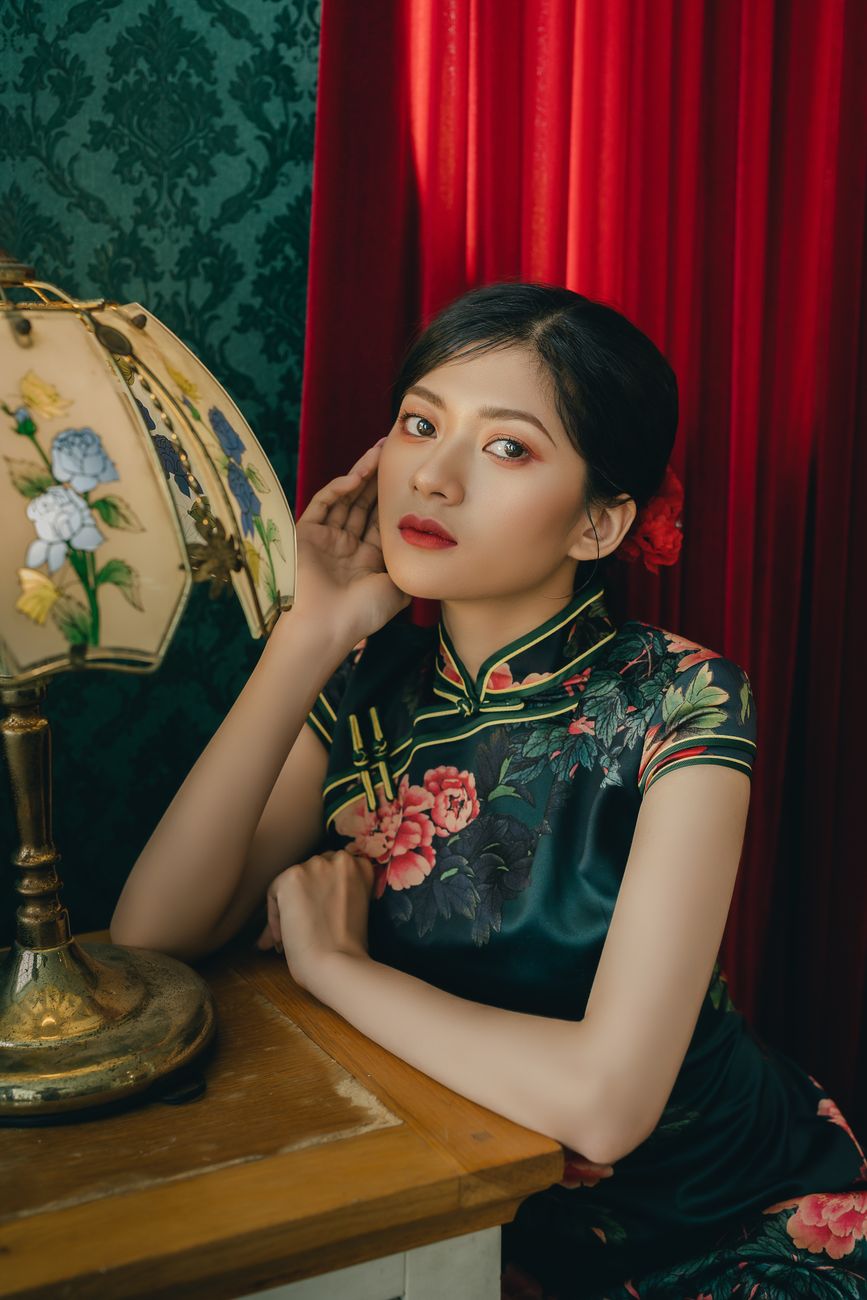 Stylish portrait of a woman in traditional attire sitting by an antique lamp in an elegant setting.