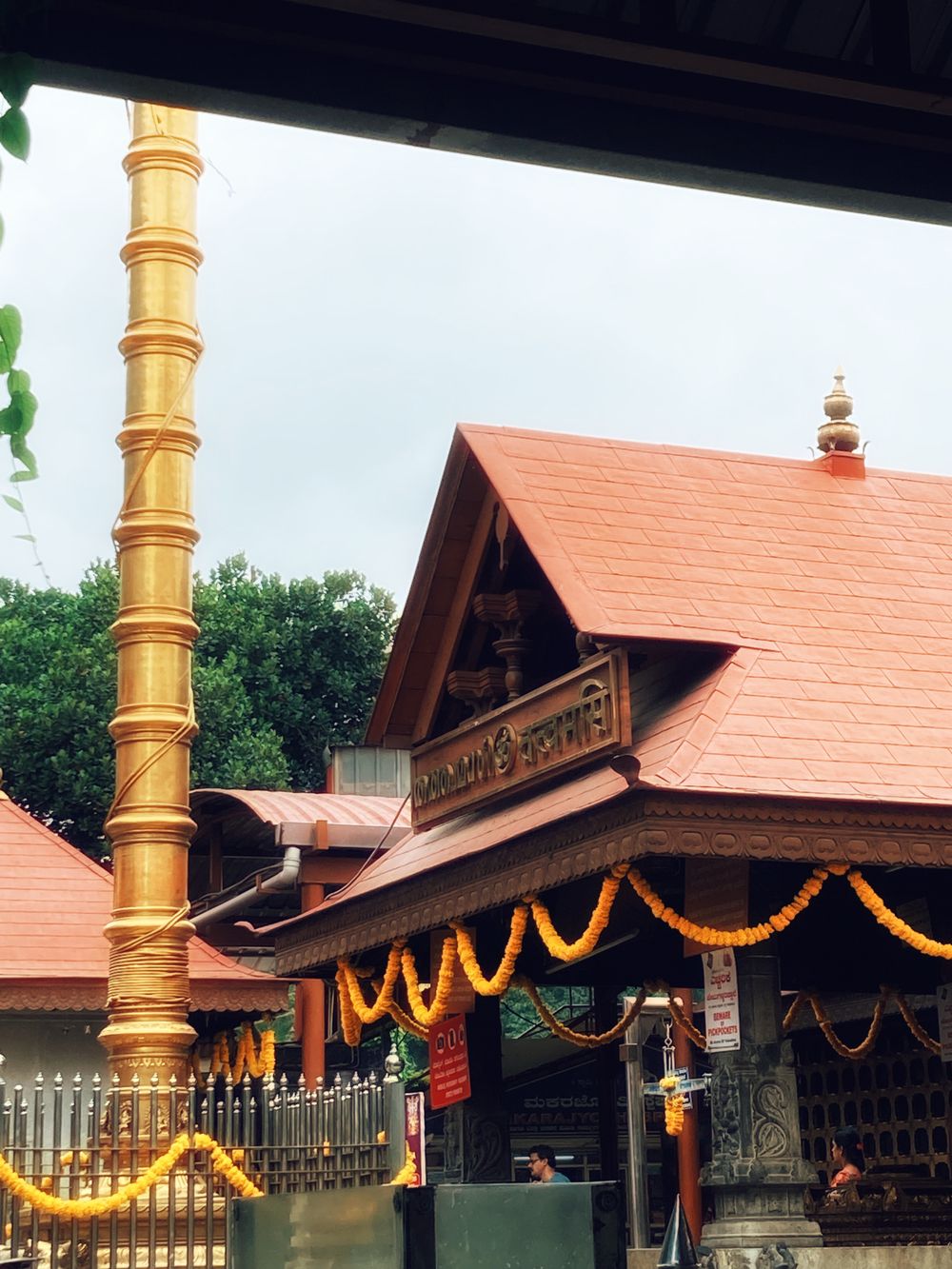 A traditional Kerala temple with a golden flagstaff and marigold garlands