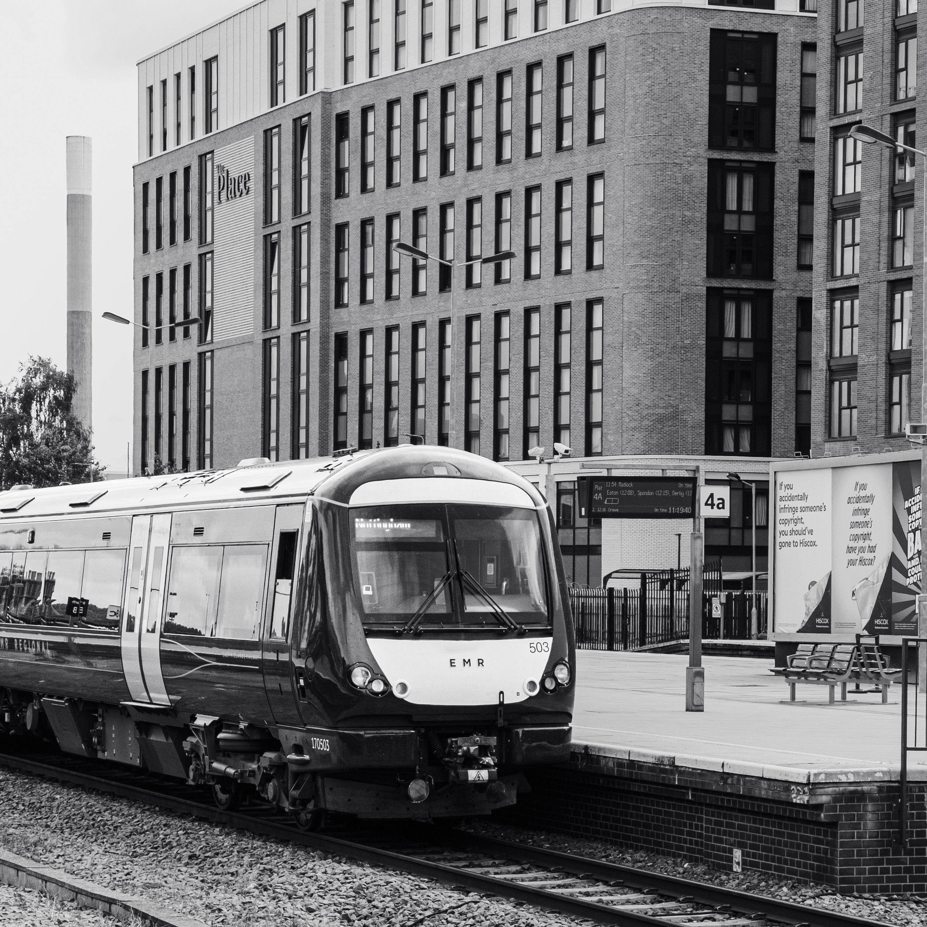 Black and white photo of a modern city train at a UK railway station in England.
