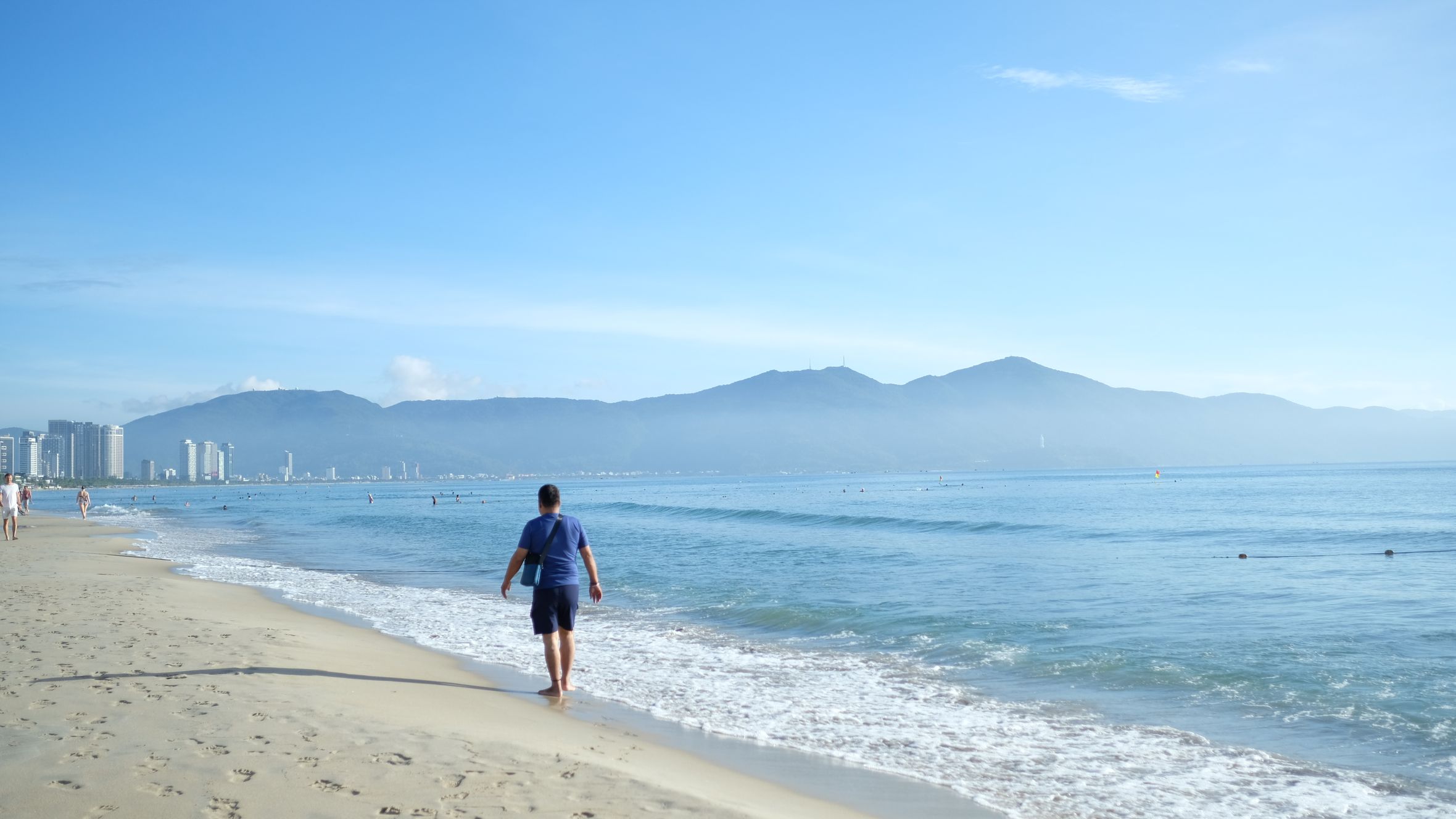 A peaceful morning stroll along Da Nang beach with stunning mountain views.