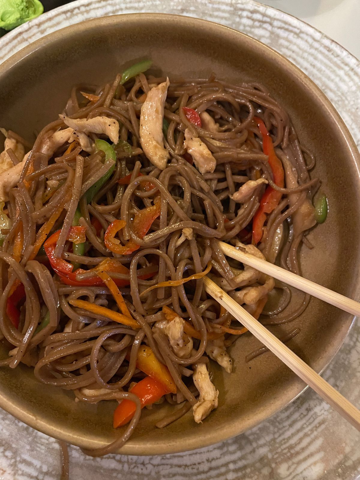 Buckwheat soba stir-fried with chicken strips, red pepper, carrot and green beans in a bowl