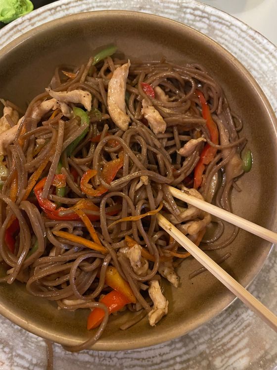Buckwheat soba stir-fried with chicken strips, red pepper, carrot and green beans in a bowl