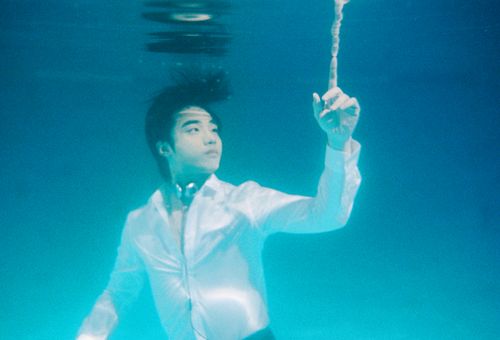 Free An artistic underwater image depicting a man in a white shirt reaching upwards, creating a dreamlike atmosphere. Stock Photo