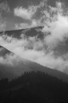 Moody and atmospheric mountains shrouded in mist and clouds, creating a dramatic scene.