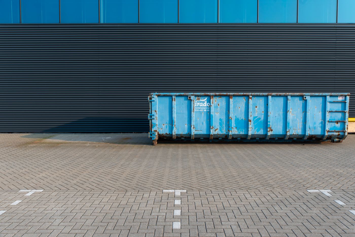 Roll-off dumpster container positioned beside a residential building for a home cleanout project