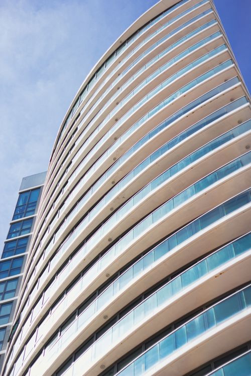 Free A modern skyscraper with a curved glass facade set against a clear blue sky, showcasing contemporary architecture. Stock Photo