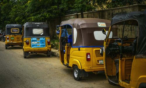 Free Auto rickshaws parked on a quiet street in Kaduna, Nigeria, showcasing vibrant colors and local life. Stock Photo