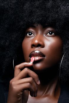Stunning close-up of a woman with dense afro hair applying lipstick.