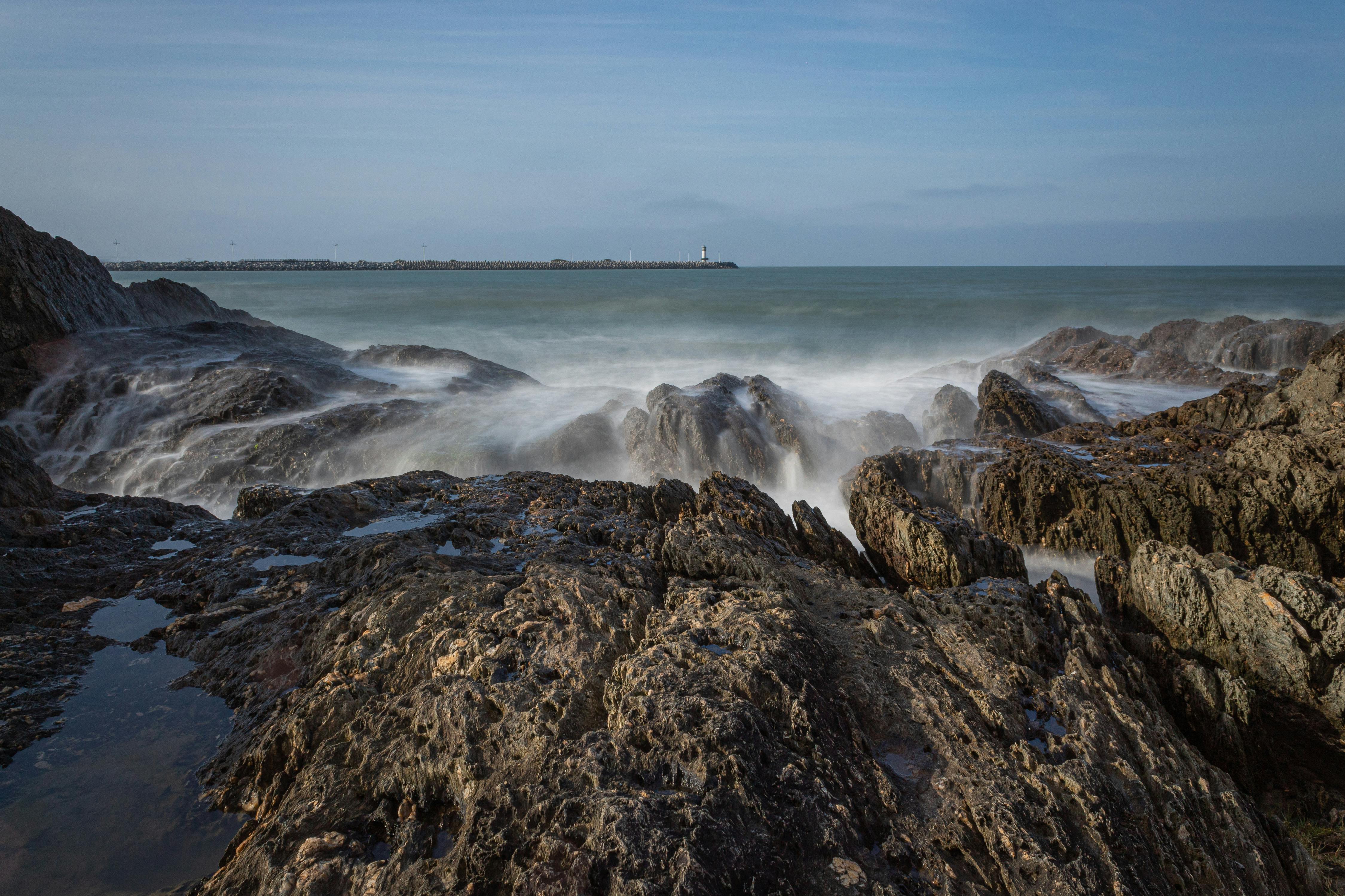 Long exposure of ocean waves crashing over rocky shoreline in Santa Catarina, Brazil.