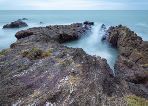 Dramatic long exposure of ocean waves crashing on rocky coast in Santa Catarina, Brazil.