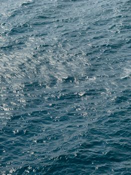 Vibrant ocean waves captured in sunlight, highlighting texture and movement in the deep blue sea.
