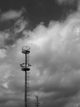 Black and white photo capturing industrial towers silhouetted against a dramatic cloudy sky.