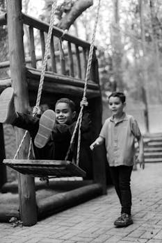 Children playing on a swing set in a park, capturing fun and joy.