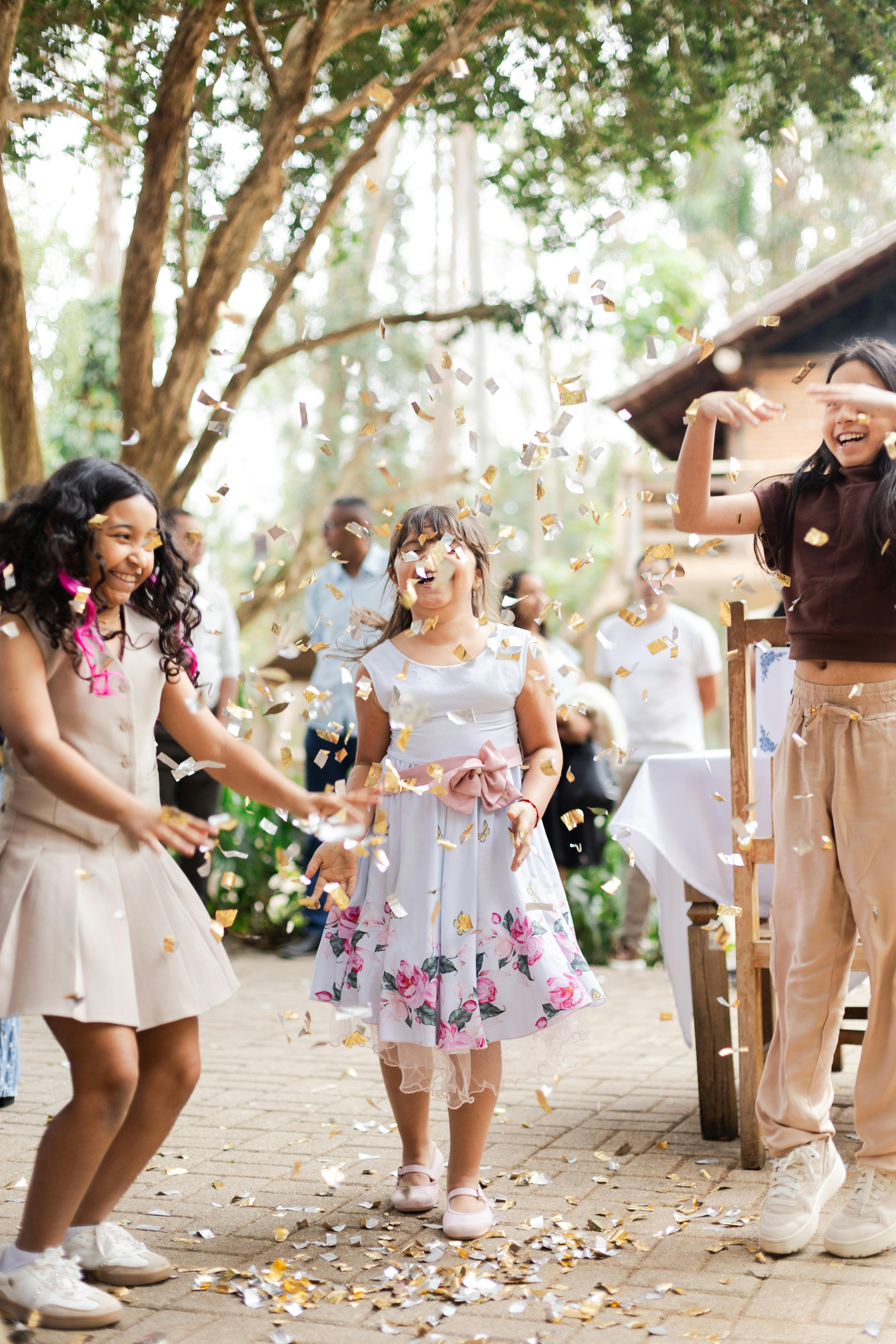Children enjoying an outdoor wedding celebration with confetti and laughter.