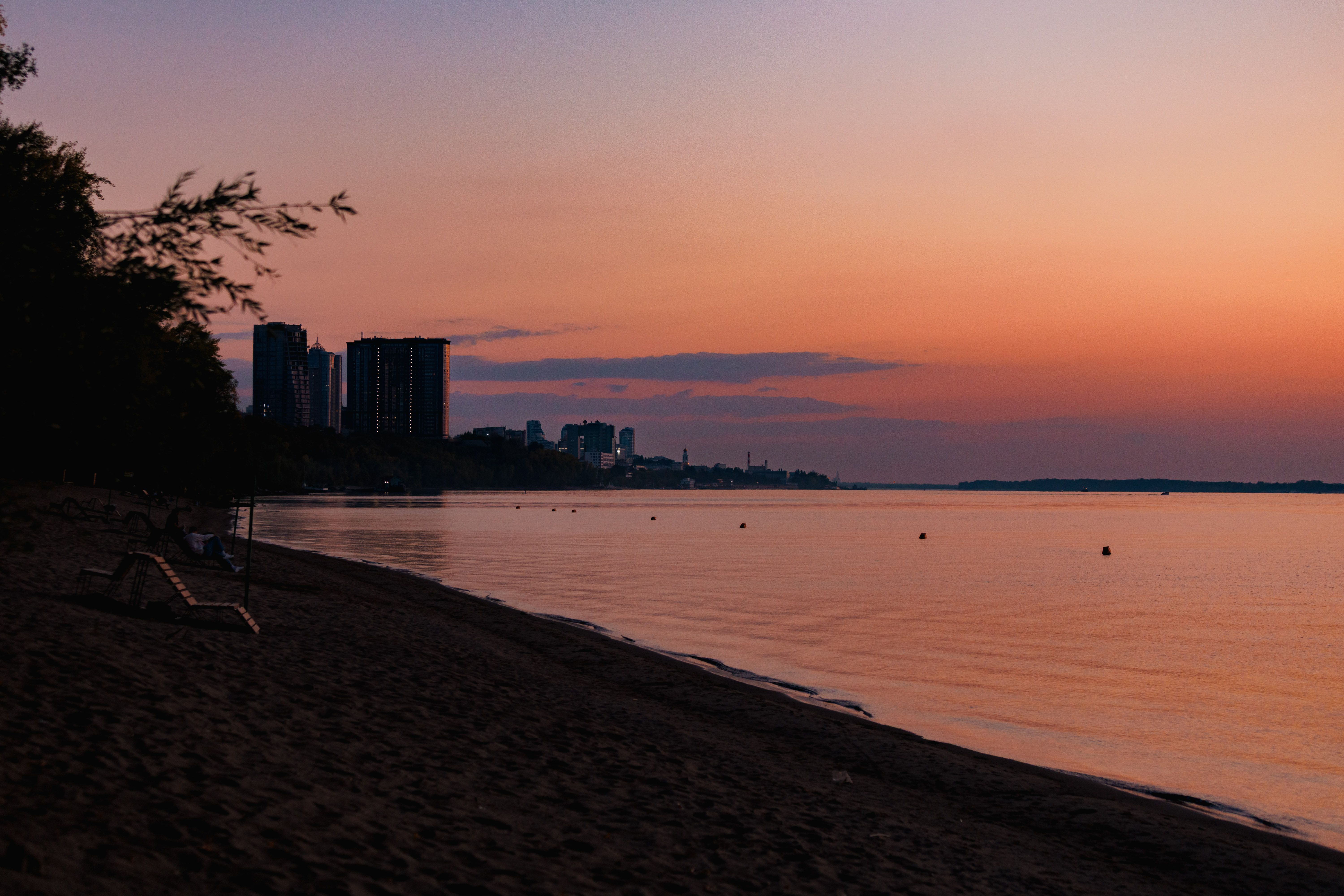 Sunset Over Beach with City Skyline View · Free Stock Photo
