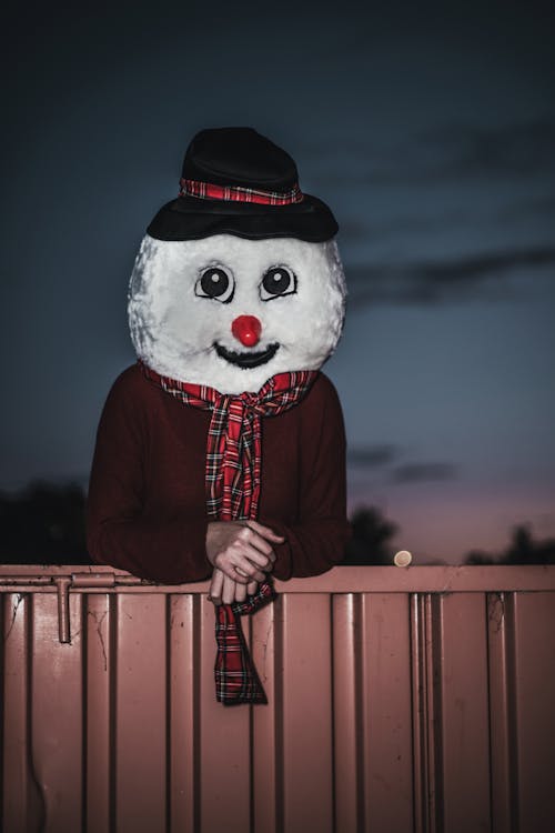 Man Wearing Snowman Costume Behind Beige Wall