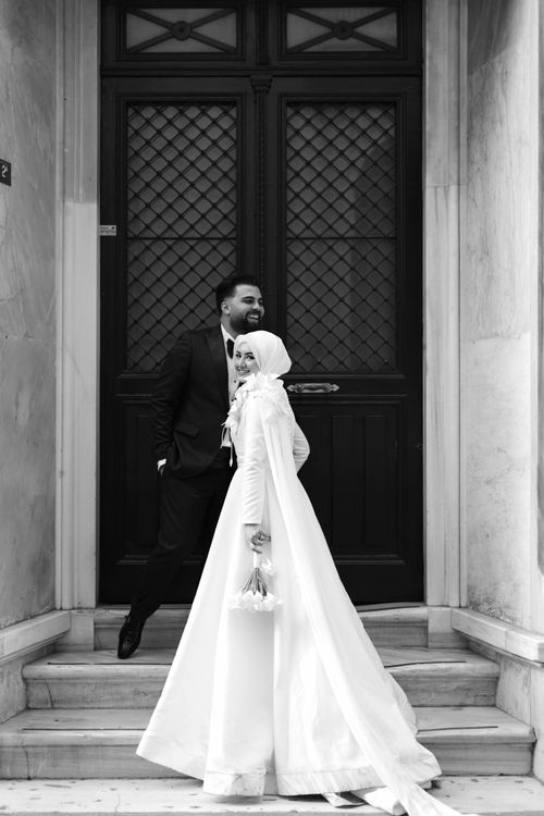 Free Stylish outdoor wedding portrait with bride in hijab and groom laughing, monochrome elegance. Stock Photo