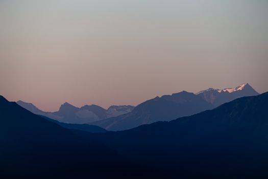 Peaceful twilight scene of a mountain range with pastel skies and a serene atmosphere.