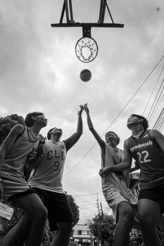 Dramatic shot of teenagers playing street basketball, reaching for the hoop.