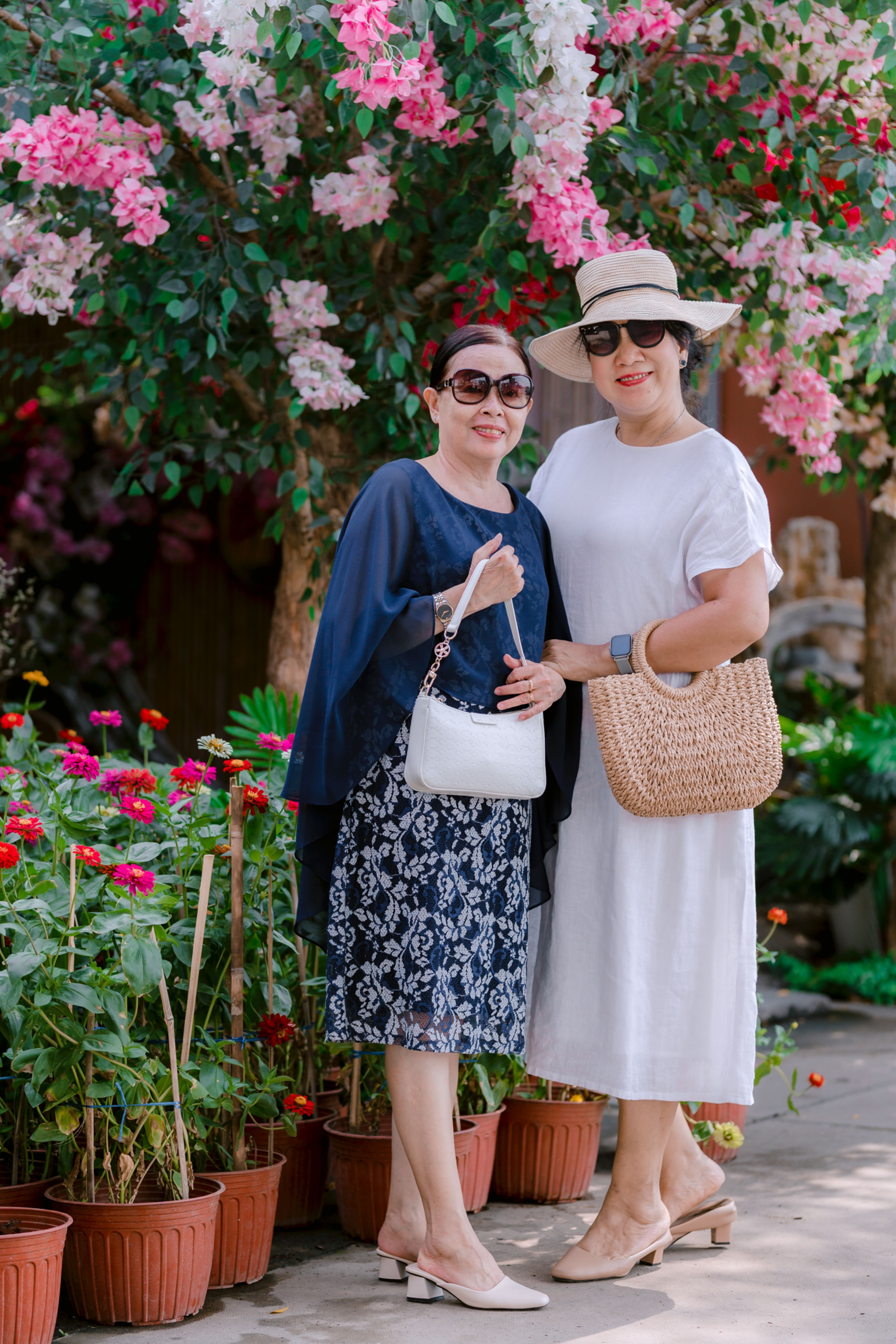 Two Stylish Women Posing in a Floral Garden · Free Stock Photo