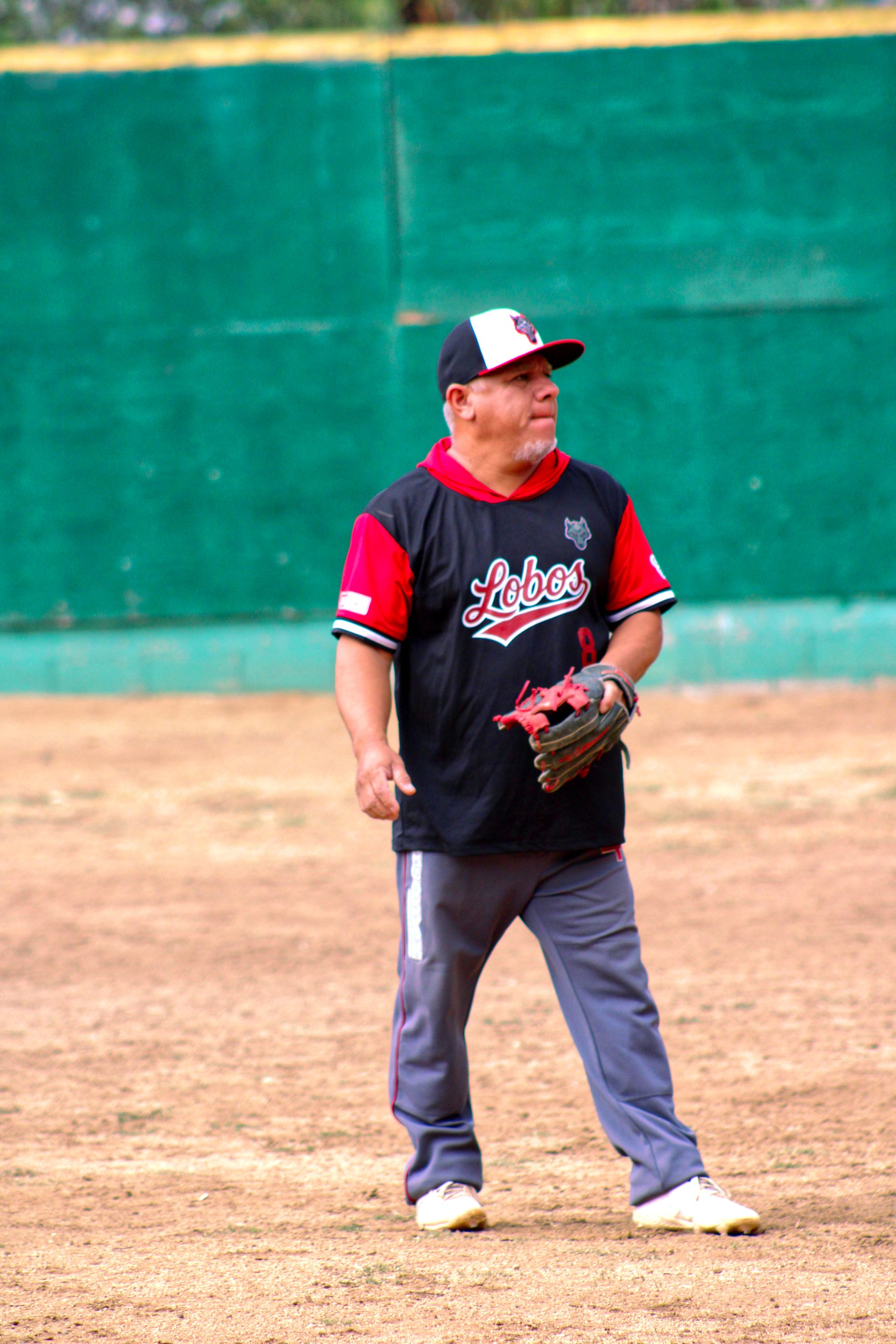 Adult male baseball player standing on a dusty field ready for play.