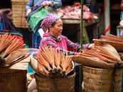 A woman selling traditional incense sticks at a vibrant market in Lào Cai, Vietnam.