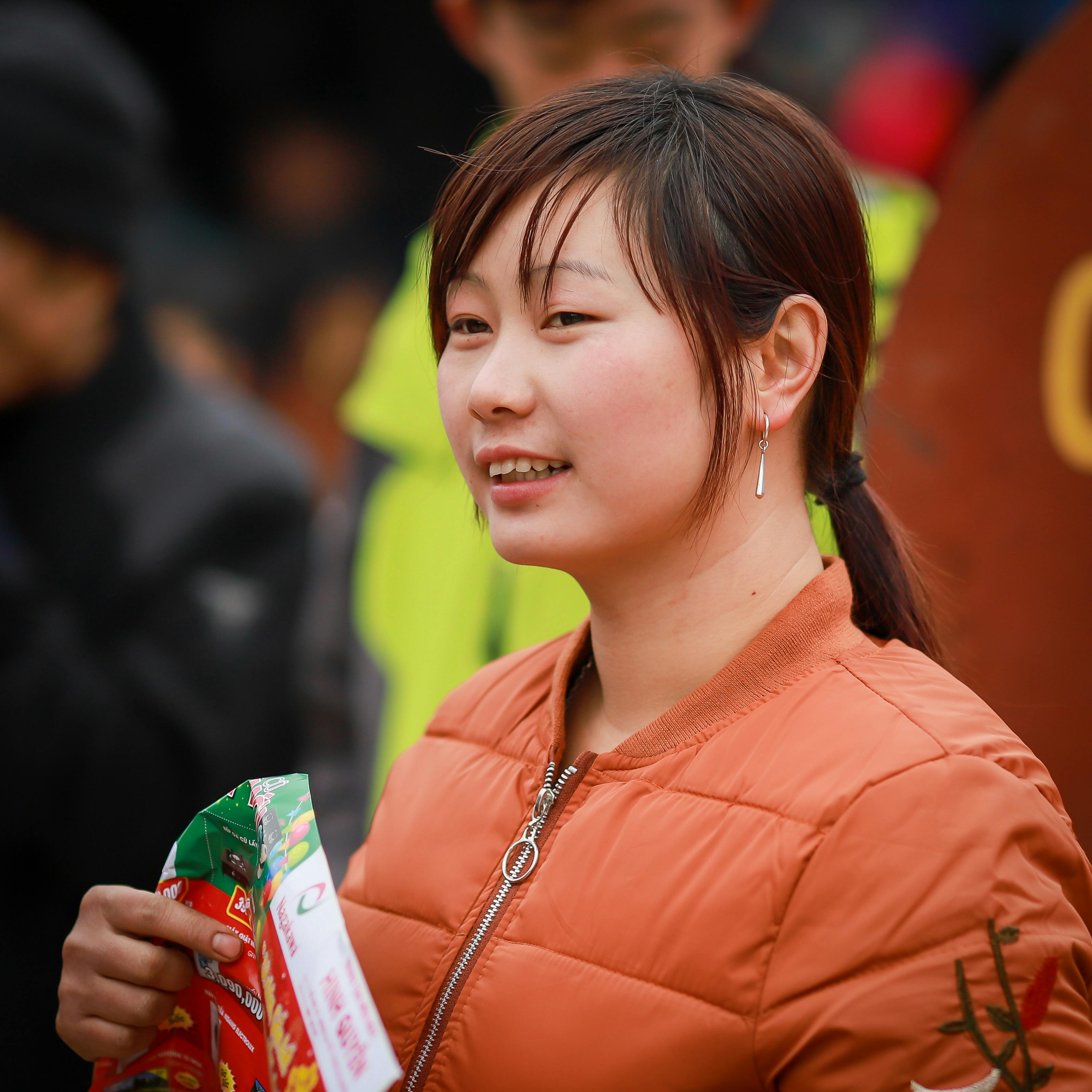 A young woman in Lào Cai, Vietnam, holding packaged goods at an outdoor market.