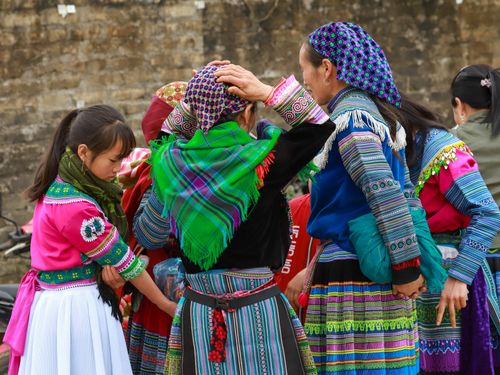 Free Women and a child in traditional attire at an outdoor market in Lào Cai, Vietnam, showcasing vibrant cultural garments. Stock Photo