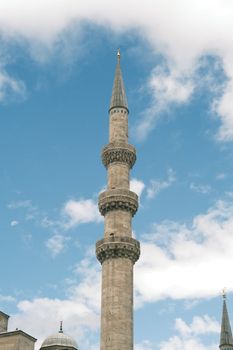 A towering minaret from the Süleymaniye Mosque in Istanbul under a clear blue sky.