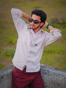 Portrait of a stylish young man wearing sunglasses and a casual shirt, enjoying a relaxed moment outdoors.