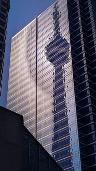 Capture of CN Tower reflecting on modern skyscraper in downtown Toronto.
