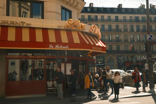 Lively street scene outside La Rotonde Brasserie in Paris on a sunny day.
